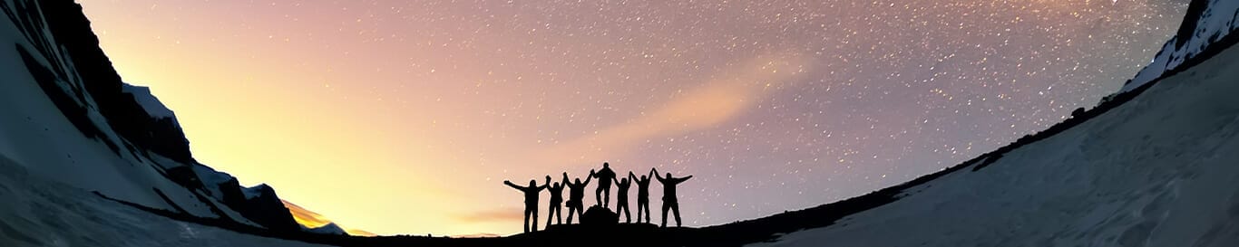 sillhouette of people standing in a snowy mountain region with stars behind them
